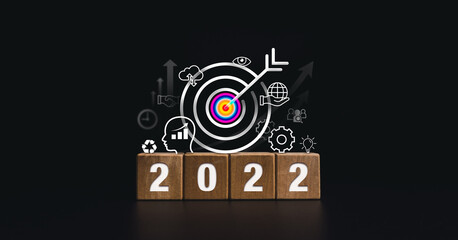 2022 Happy New year banner with big goal target and successful concept. The 2022 numbers on wooden cube blocks with business strategy icons on dark background, modern and minimal style.