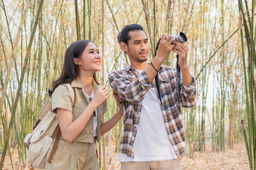 Fototapeta premium Beautiful, Happy asian young man,woman smile and look at camera after boyfriend take photo, picture of her while traveling together at forest, nation park. Summer vacation outdoor with couple concept.