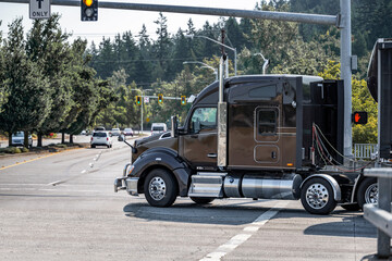 Black stylish compact cab big rig semi truck tractor transporting cargo in tented semi trailer...