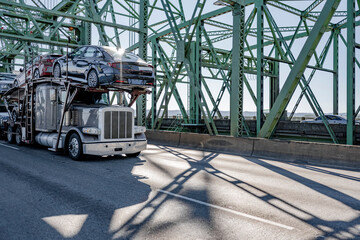 Industrial car hauler big rig gray semi truck transporting cars on modular semi trailer running on...