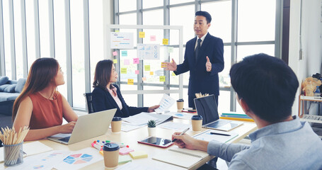 Fototapeta premium Happy business people meeting present graph chart investment, business data in meeting room. Group of business people meeting in conference room. Asian businessman speech, present teamwork partnership