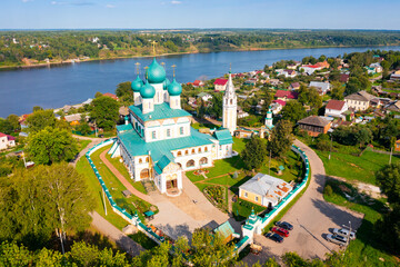 Scenic aerial view of Orthodox Resurrection Cathedral on background of green townscape of Tutayev and Volga river on summer day, Yaroslavl region, Russia