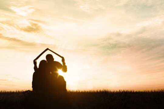 Silhouette of young family holds house roof symbol