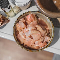 Fresh raw chicken meat in a ceramic bowl on kitchen wood table for cooking.
