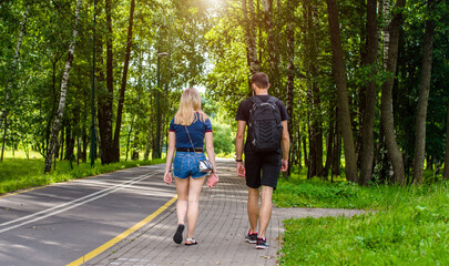 Fototapeta premium A guy and a girl walk along the path in the city Park
