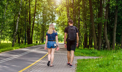 A guy and a girl walk along the path in the city Park