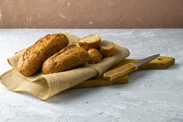 two fresh rye buns on burlap one of the buns is cut next to a knife