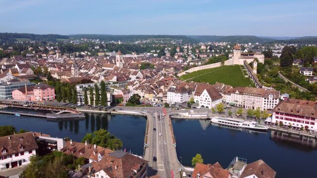 Aerial drone footage of the Schaffhausen old town by the Rhine river on a sunny summer day in eastern Switzerland with the famous Munot medieval fortress. 
