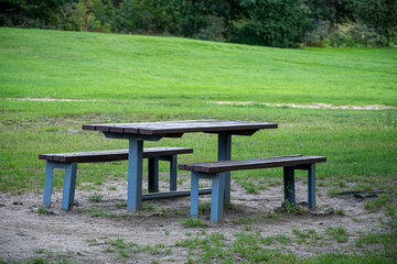 Outdoor table and benches in a park, Vilnius, Lithuania. Picnic space in the city. Green lawn, warm summer day. Selective focus on the furniture, blurred background.