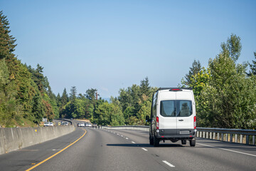 White compact mini van for commercial transportation freights driving on the divided highway road