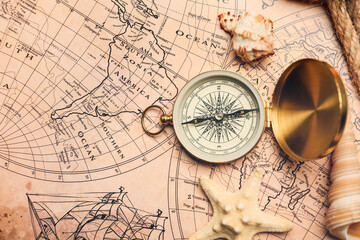 Fototapeta na wymiar Old compass with sea shells on vintage world map