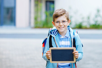 Happy little kid boy with backpack or satchel and glasses. Schoolkid on the way to school. Healthy...