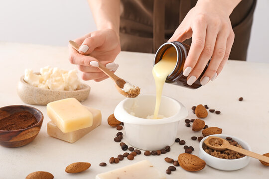 Woman making natural soap on light background
