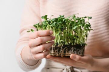Woman with fresh micro greens on light background, closeup