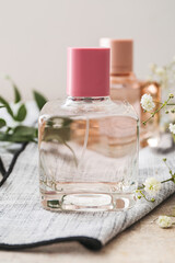 Bottle of perfume and gypsophila flowers on light background, closeup