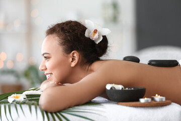 Beautiful young African-American woman relaxing in spa salon