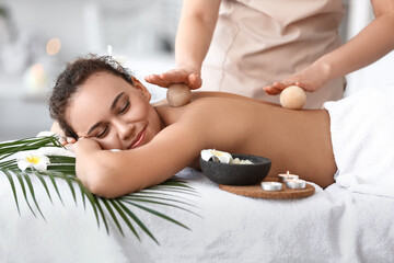 Fototapeta na wymiar Beautiful young African-American woman getting massage in spa salon