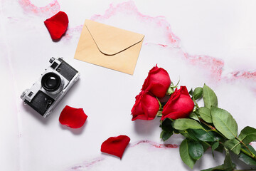 Beautiful roses, photo camera and envelope on light background