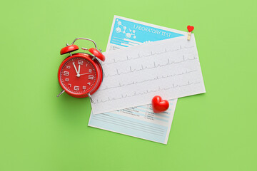 Red alarm clock with cardiogram and laboratory test on green background, top view