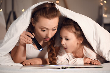 Little girl and her mother with flashlight reading bedtime story - obrazy, fototapety, plakaty