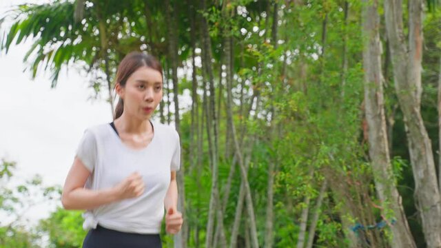 Asian young beautiful sport woman running on street in public park.