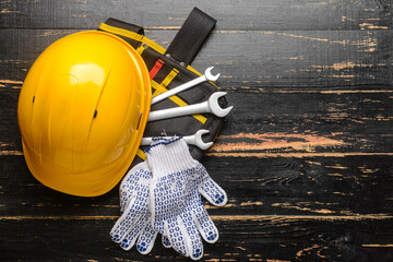Hardhat with builder's supplies on dark wooden background