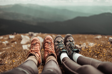 Female hiker feet in trekking boots relaxing after a long hike on the top of a mountain on sunny...