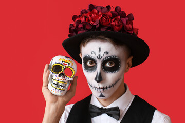 Young man with painted face and sugar skull for Mexico's Day of the Dead (El Dia de Muertos) on...