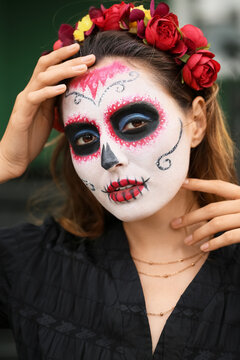 Young woman with painted skull on her face outdoors. Celebration of Mexico's Day of the Dead (El Dia de Muertos)