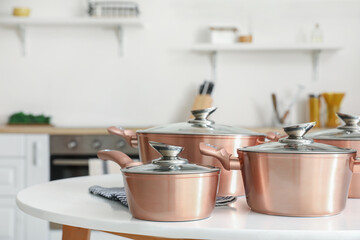 Set of copper cooking pots on table in kitchen