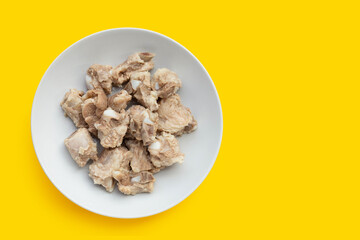 Boiled pork ribs in white plate on yellow background.