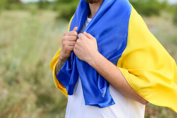 Young man with Ukrainian flag outdoors