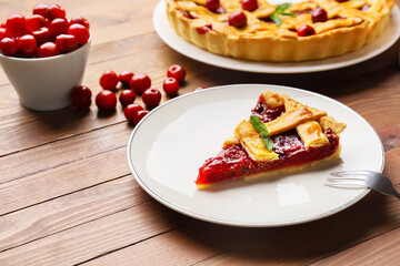 Plate with piece of tasty cherry pie on wooden background, closeup