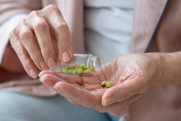 Woman's hand is holding a medicine in close-up, an elderly woman is holding a pill in her hands, pouring pills out of a bottle.