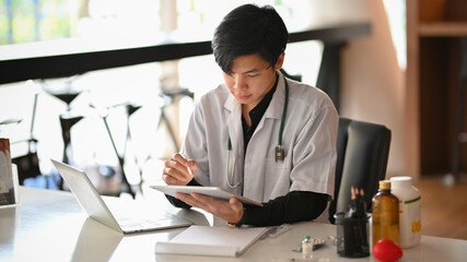 Male doctor working and checking medical case in his office