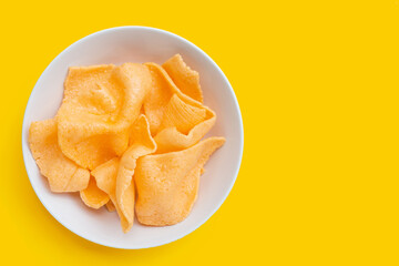Prawn crackers in white bowl on yellow background. Shrimp crispy rice snack