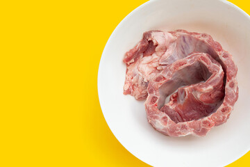 Raw pork ribs in white bowl on yellow background.
