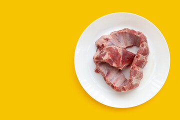 Raw pork ribs in white plate on yellow background.