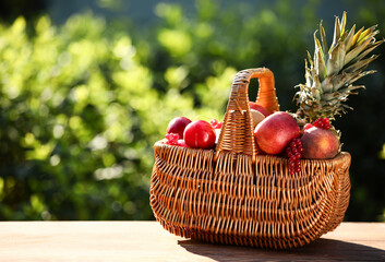 Wicker basket with fresh fruits on table outdoors