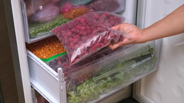 Frozen berries. Frozen food storage. Home stock shelf. A raw food diet. Plastic boxes and bags with sliced berries and fruits