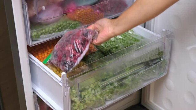 Frozen berries. Frozen food storage. Home stock shelf. A raw food diet. Plastic boxes and bags with sliced berries and fruits
