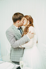 The bride and groom kiss on a white background