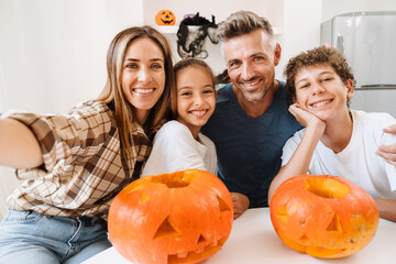 White family smiling while taking selfie photo with Halloween pumpkins