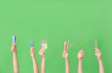 Many different hands with school supplies on green background