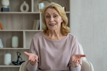 Cheerful elderly woman of the 70s talks to a webcam, communicates in an online video chat