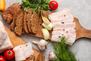 Wooden boards with salted lard and bread on light background