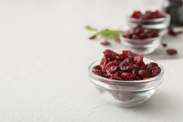 Bowl with tasty dried cranberries on light background, closeup