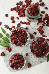 Bowls with tasty dried cranberries on light background