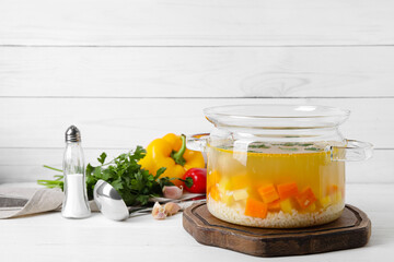 Pot with tasty meatball soup, vegetables and spices on table