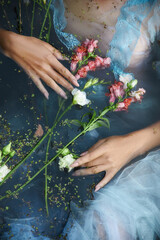 Art beautiful romantic woman lies in swamp in blue long dress with flowers. Portrait brunette in...